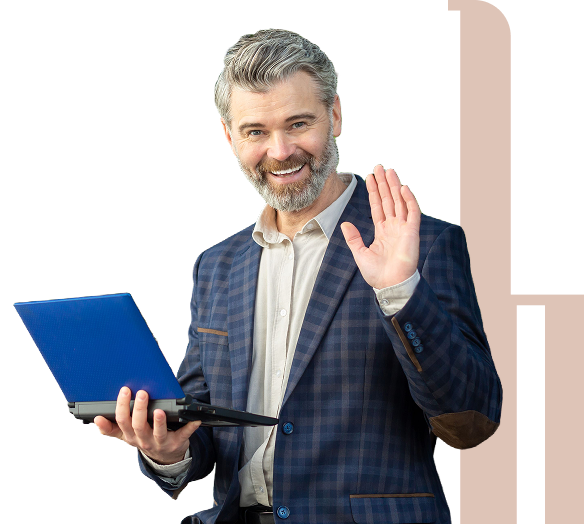 Man with gray hair and beard wearing a plaid suit holds a blue laptop in one hand and waves with the other, smiling at the camera.